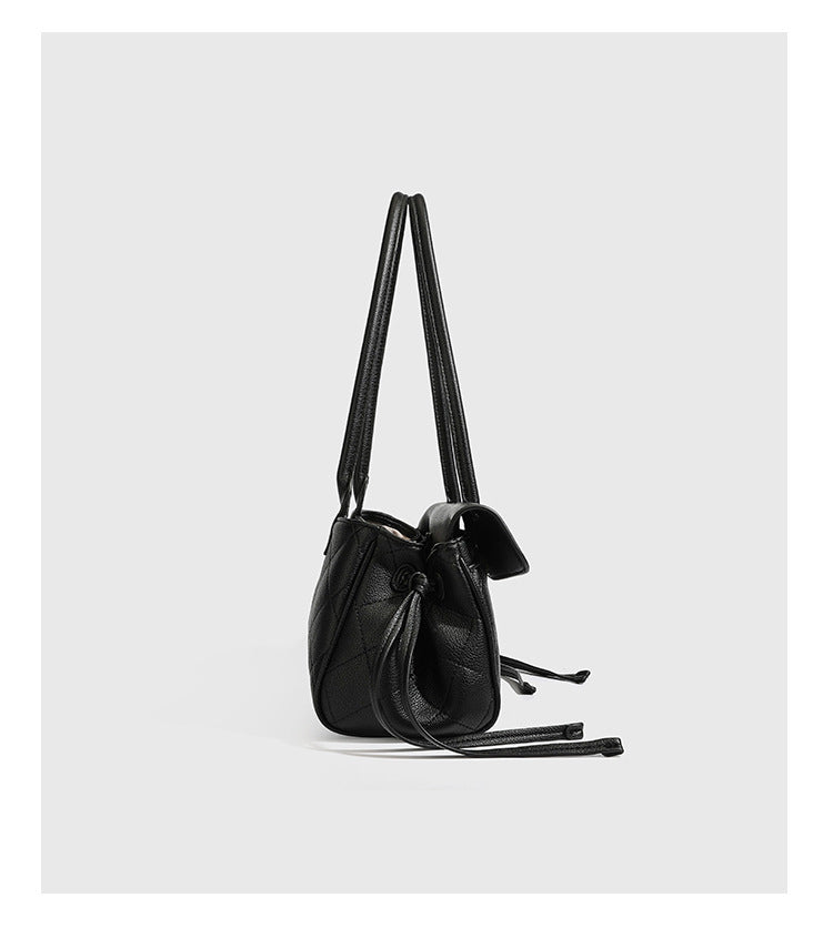 Structured black diamond-quilted shoulder bag with gold-tone turn-lock flap closure and dual round shoulder straps, detail