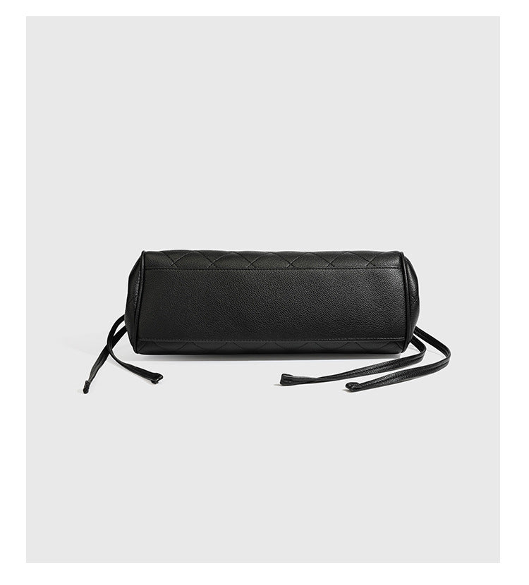 Structured black diamond-quilted shoulder bag with gold-tone turn-lock flap closure and dual round shoulder straps, detail