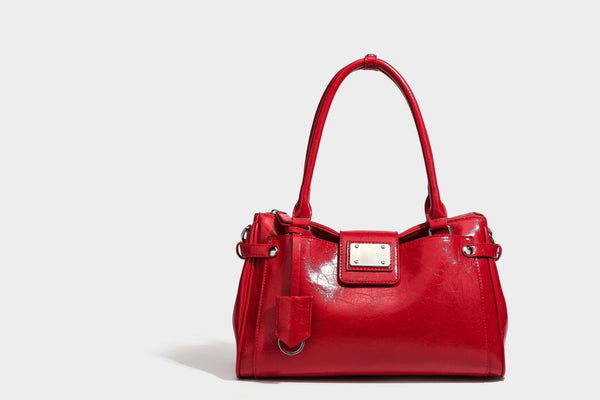 Structured glossy crinkled leather-look satchel with double top handles, front metal-plaque tab, silver-tone hardware, and
