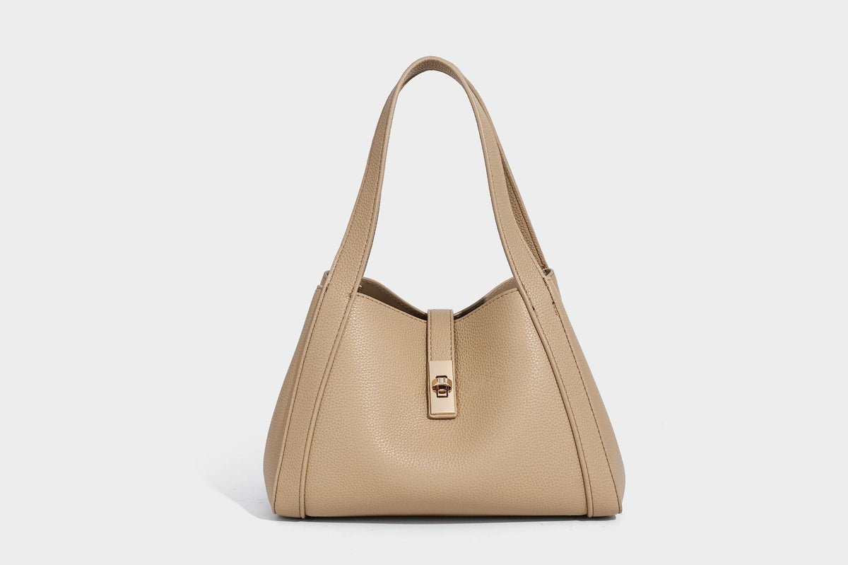 Structured trapezoid tote bag in taupe pebbled leather-look finish with gold-tone turn-lock hardware, dual top handles, and