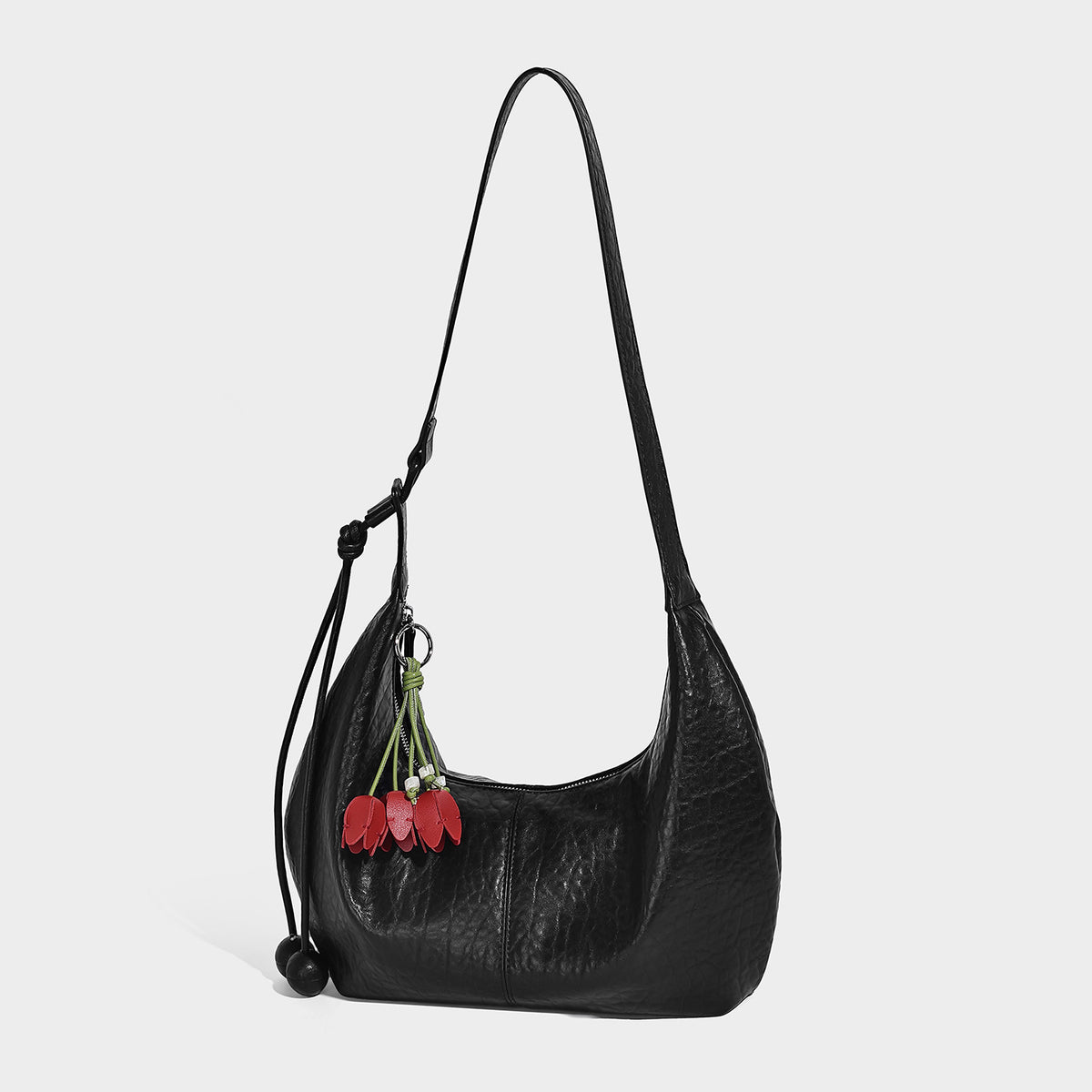 Slouchy crescent half-moon shoulder bag in pink pebbled textured finish with floral charm and knotted side detail, detail