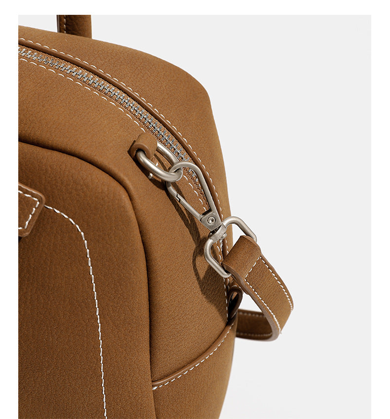 Kompakte, strukturierte Henkeltasche mit matter genarbter Oberfläche, geknoteten Doppelhenkeln, goldenem Schlüsselanhänger und abnehmbarem, Detail