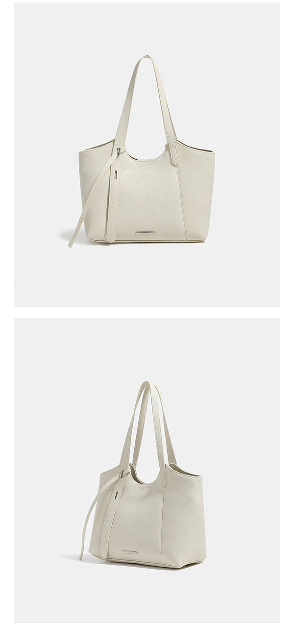 Structured trapezoidal tote bag with smooth leather-look finish, long black contrast shoulder straps, and dangling strap