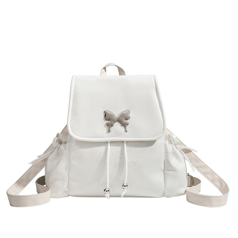 Compact white pearlescent flap backpack with silver-tone bow hardware and drawstring closure, detail view 5