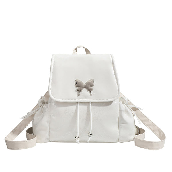 Compact white pearlescent flap backpack with silver-tone bow hardware and drawstring closure, detail view 5