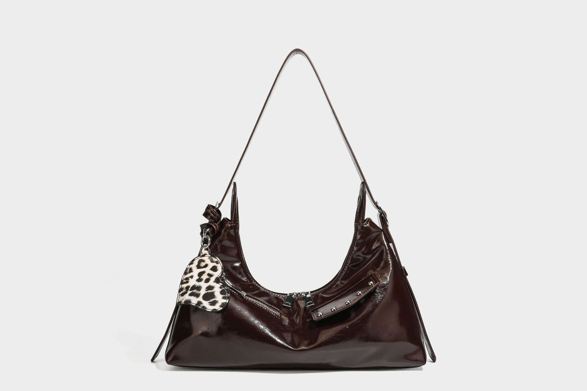 Glossy dark brown hobo shoulder bag with slim strap, front zip pocket, stud detail, and detachable leopard-print heart charm