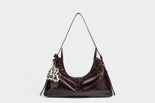 Glossy dark brown hobo shoulder bag with slim strap, front zip pocket, stud detail, and detachable leopard-print heart charm