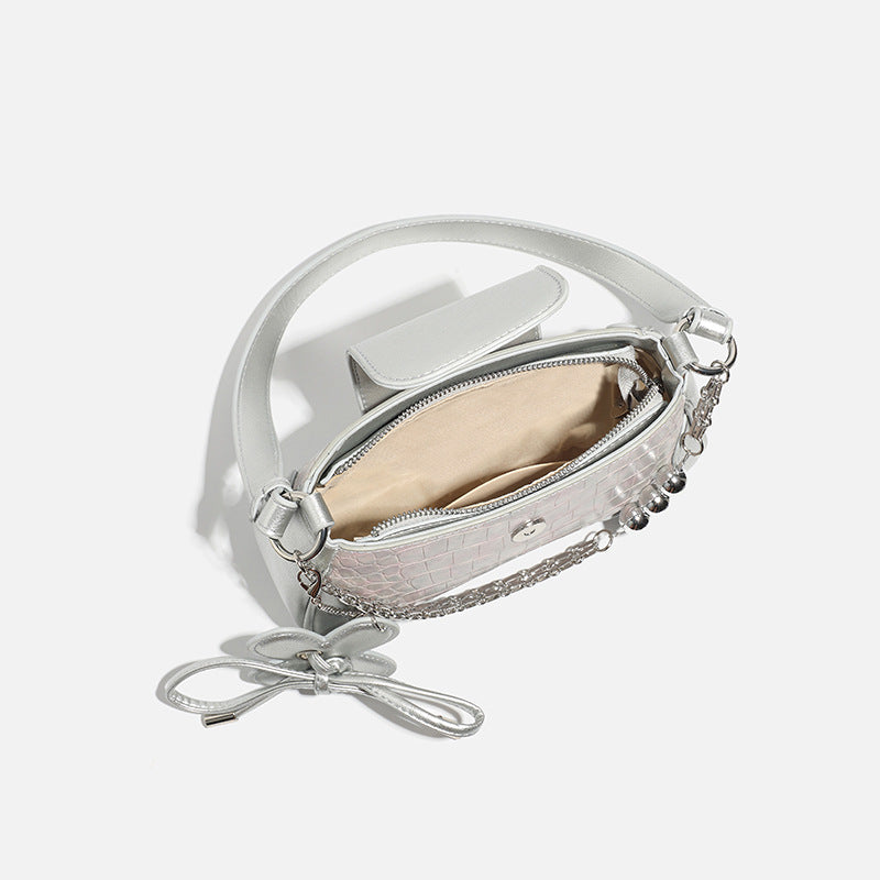Compact silver flap shoulder bag with pale-pink crocodile-embossed panel, chain bead handle, bow charm, and adjustable
