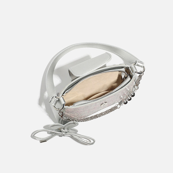 Compact silver flap shoulder bag with pale-pink crocodile-embossed panel, chain bead handle, bow charm, and adjustable