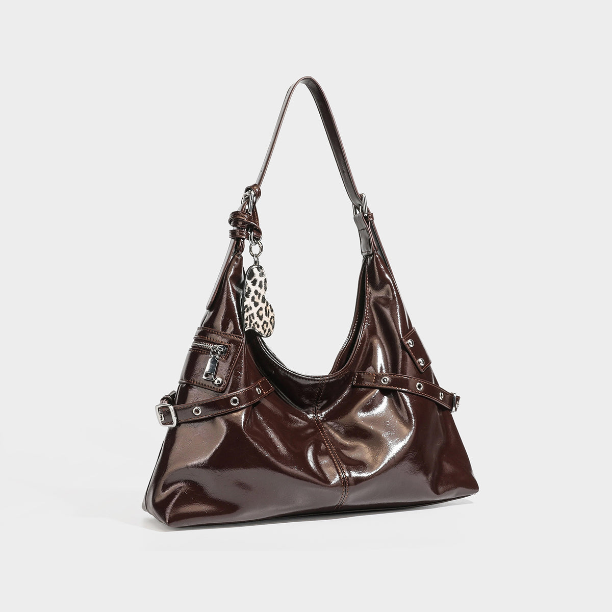 Glossy dark brown slouchy hobo shoulder bag with silver grommet strap detail, front zip pocket, and leopard-print heart