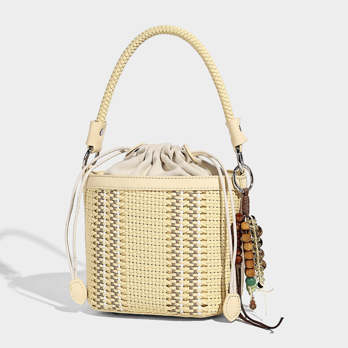 Small woven bucket bag with drawstring top, braided handle, detachable crossbody strap, and silver-tone ring hardware, detail