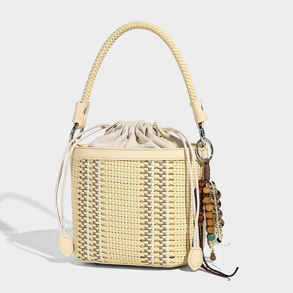 Small woven bucket bag with drawstring top, braided handle, detachable crossbody strap, and silver-tone ring hardware, detail
