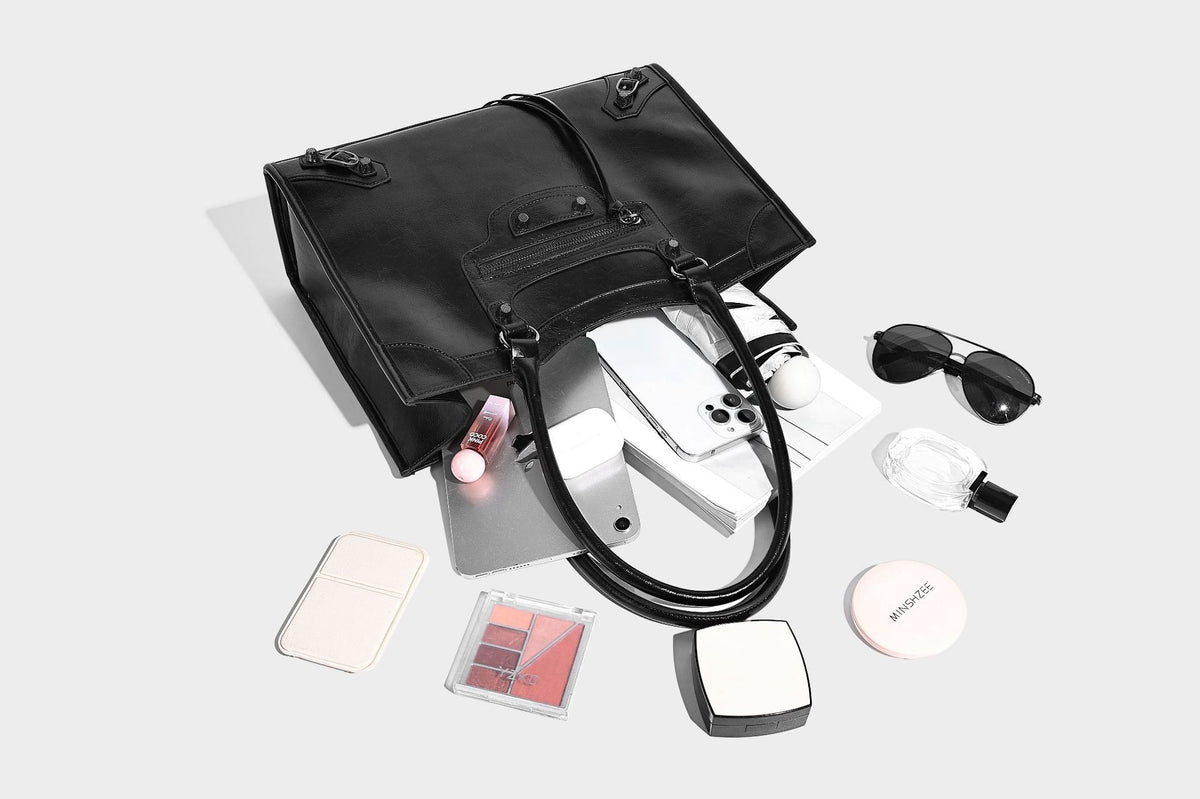 Large structured leather-look tote bag with front zip pocket, moto hardware accents, and long double shoulder straps, detail