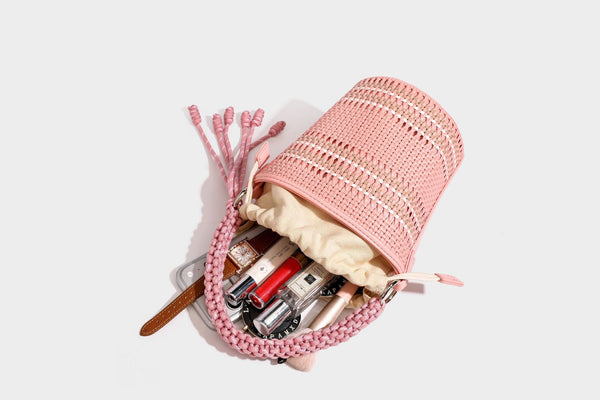 Detailansicht einer zylindrischen, handgeflochtenen Beuteltasche mit geflochtenem Henkel, Kordelzugverschluss, Kordelquasten und Metallringbeschlägen