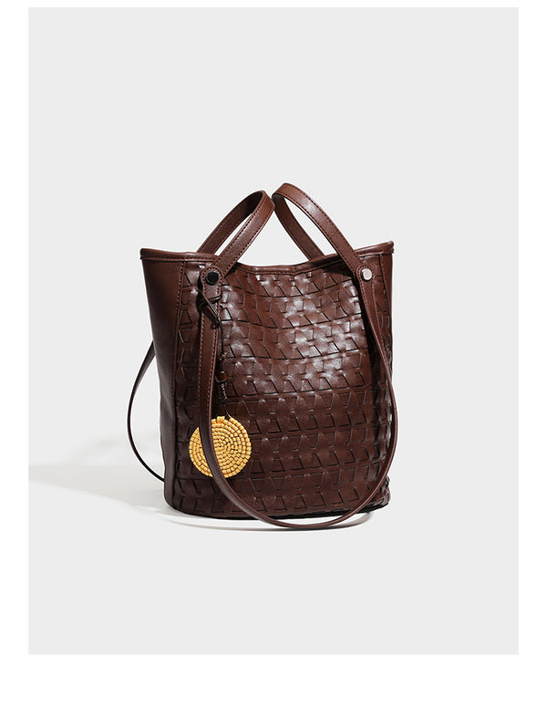 Brown embossed geometric woven leather-look bucket tote bag with dual shoulder straps, side snap hardware, and a round