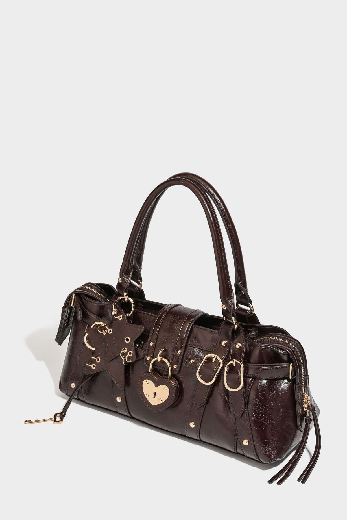 Glossy dark brown structured Boston satchel with heart-shaped lock charm, star pendant, rivet studs, multi-strap front panel