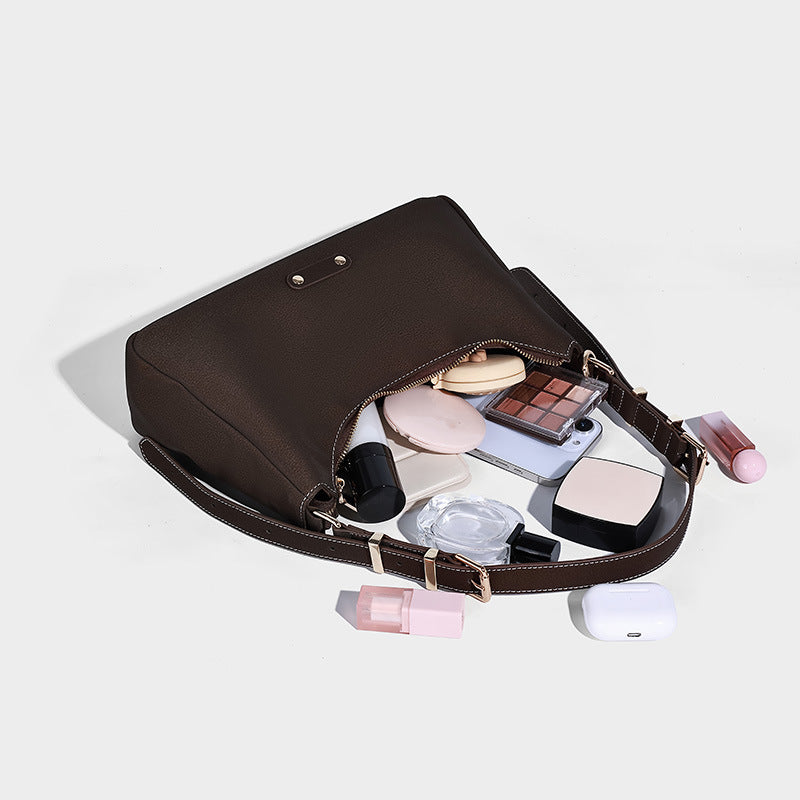 Crescent hobo shoulder bag in pebbled leather-look finish with top zipper, adjustable strap, gold-tone ring hardware, and