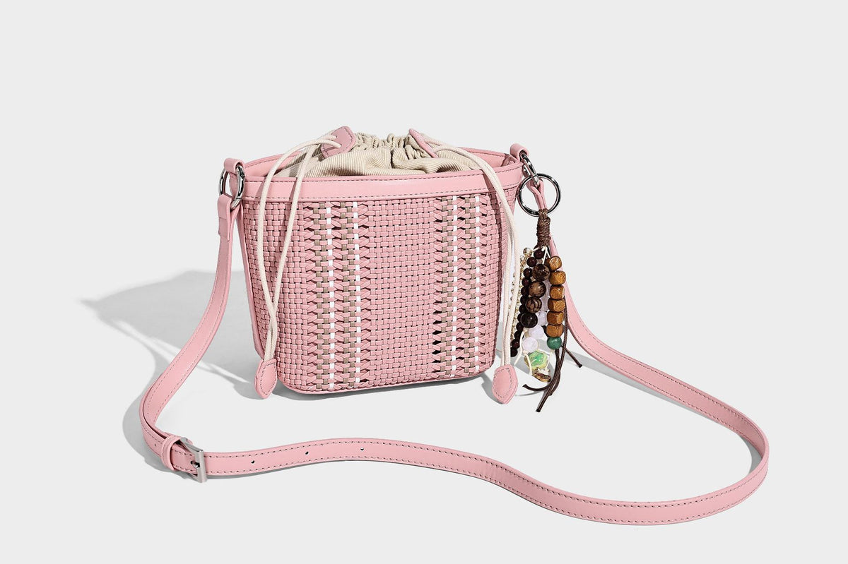 Small woven bucket bag with drawstring top, braided handle, detachable crossbody strap, and silver-tone ring hardware, detail