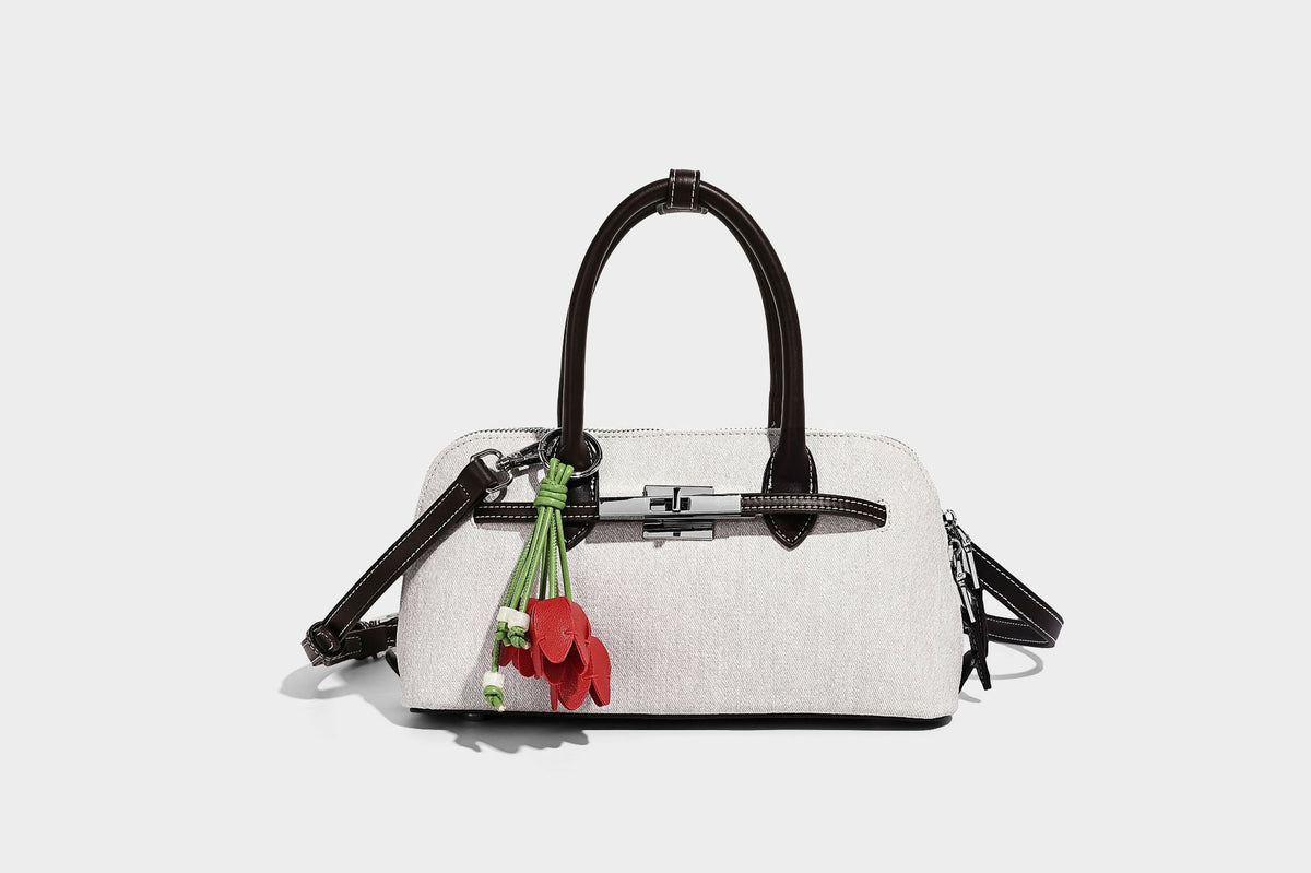 Compact structured satchel in light blue denim-look fabric with black leather-look trim, silver turn-lock closure, rolled