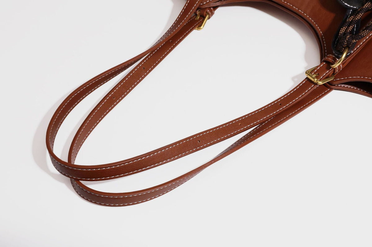 Structured smooth leather-look tote bag with long shoulder strap, gold-tone hardware, and hanging tassel-coin charm, detail