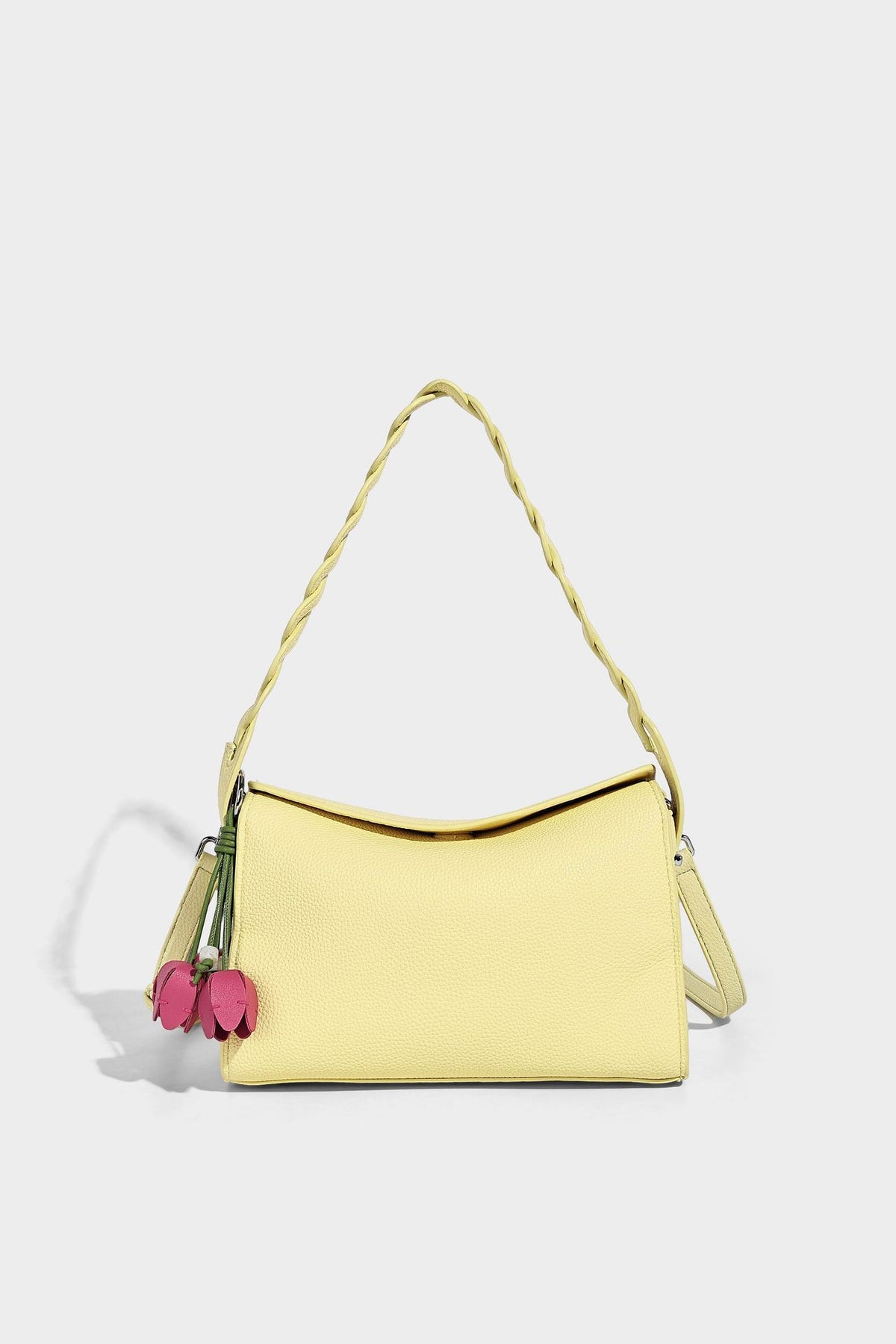 Small structured pebbled-finish shoulder bag with braided top handle, detachable crossbody strap, floral tassel charm, and