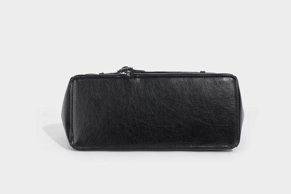Structured black leather-look satchel bag with silver padlock hardware, front zip pockets, key charms, and top handles