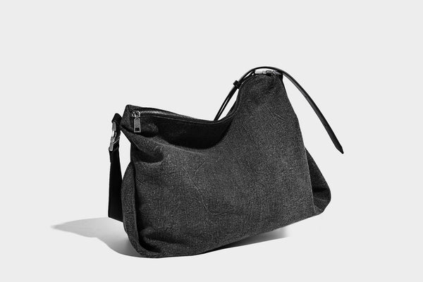 Charcoal denim-textured slouchy hobo bag with zip-top closure, silver-tone hardware, and adjustable leather-look crossbody