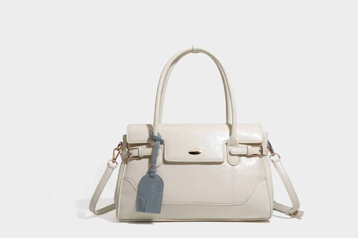 Structured glossy leather-look satchel bag with flap closure, gold-tone buckle accents, double top handles, detachable