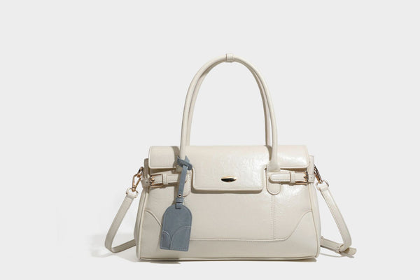 Structured glossy leather-look satchel bag with flap closure, gold-tone buckle accents, double top handles, detachable