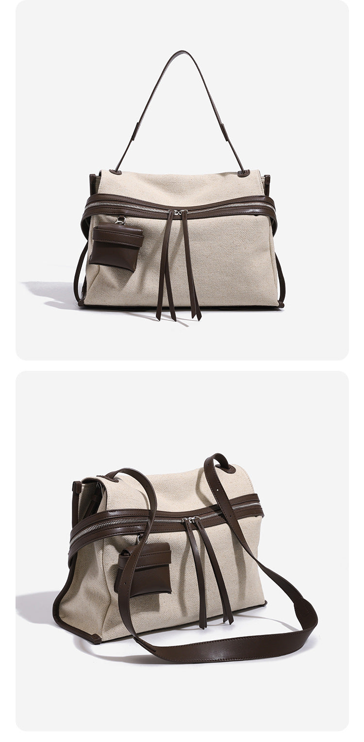 Cream canvas zip-top shoulder bag with cognac leather-look trim, dual zipper, attached mini pouch, and tassel strap ties