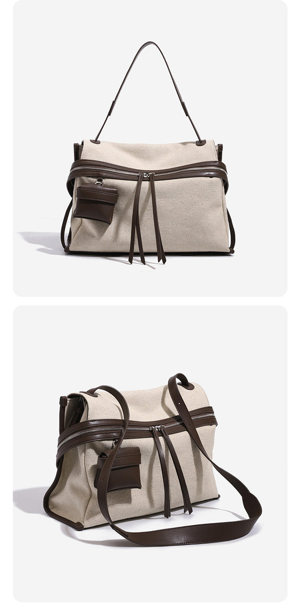 Cream canvas zip-top shoulder bag with cognac leather-look trim, dual zipper, attached mini pouch, and tassel strap ties