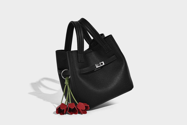 Small structured pebbled bucket tote bag with dual top handles, silver turn-lock front pocket, and detachable shoulder strap