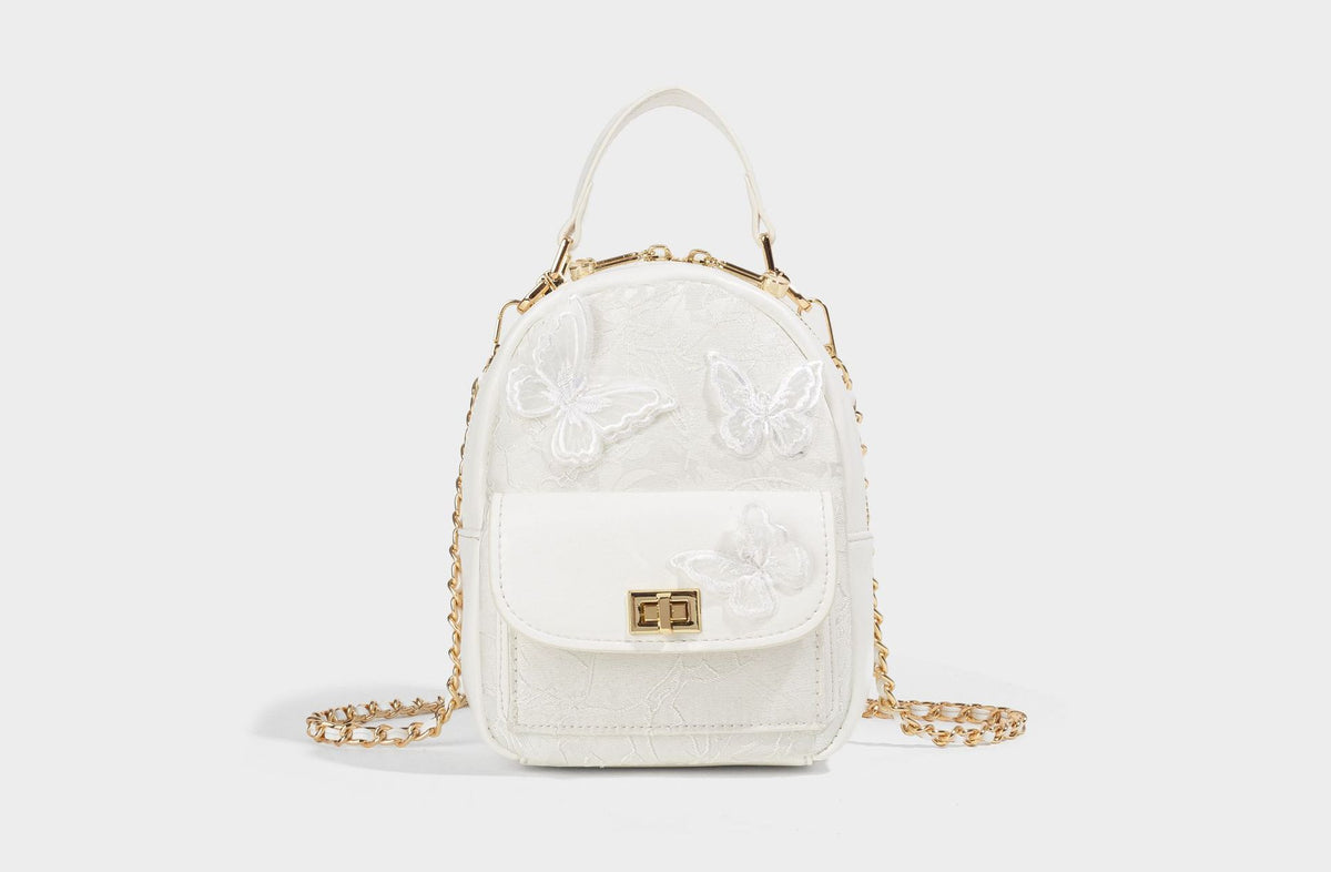 Structured mini backpack handbag with butterfly embroidery, gold-tone chain strap, and turn-lock front flap pocket, detail