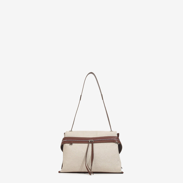 Cream canvas tote bag with brown leather-look trim, dual exterior zip pockets, long shoulder strap, and black flower charm