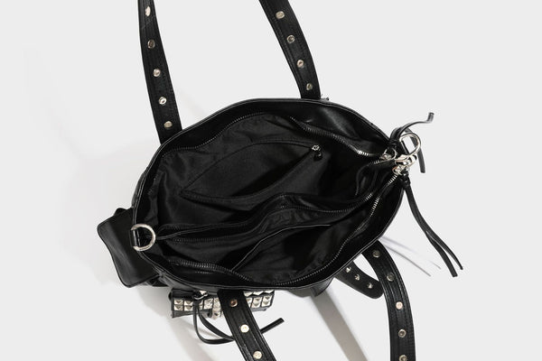 Black leather-look tote bag with silver pyramid studs on handles and front panel, multiple flap and zip exterior pockets