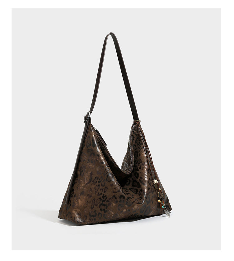 Slouchy leopard print hobo shoulder bag with glossy coated finish, top zipper closure, dark brown trim, and dangling charm