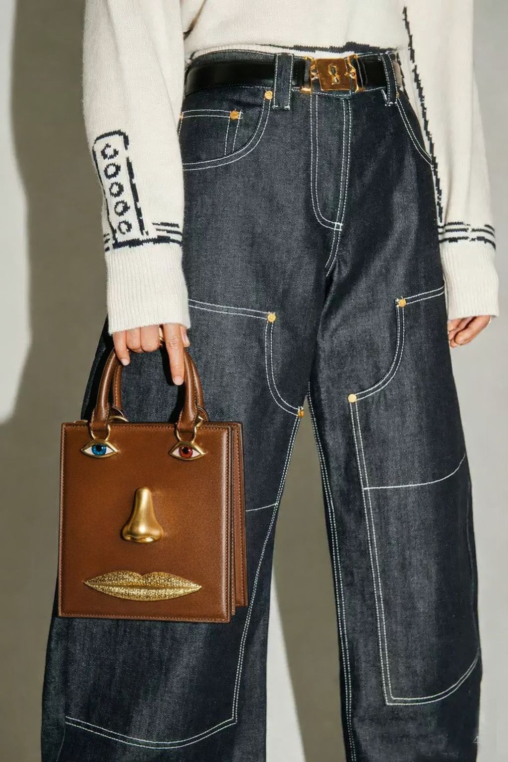Structured rectangular top-handle bag in tan leather-look finish with gold-tone sculptural face hardware including