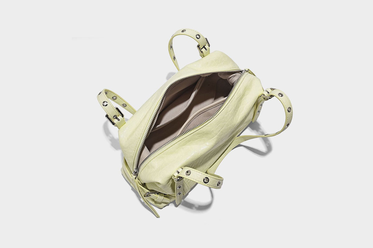 Pale yellow leather-look barrel bag with silver grommet-studded shoulder straps, top zip closure, and pink tulip floral