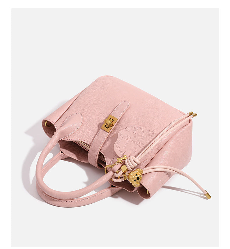 Small structured pebbled leather-look mini tote bag with gold-tone hardware, front toggle closure, knotted bear tassel charm