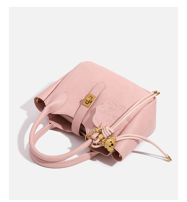 Small structured pebbled leather-look mini tote bag with gold-tone hardware, front toggle closure, knotted bear tassel charm