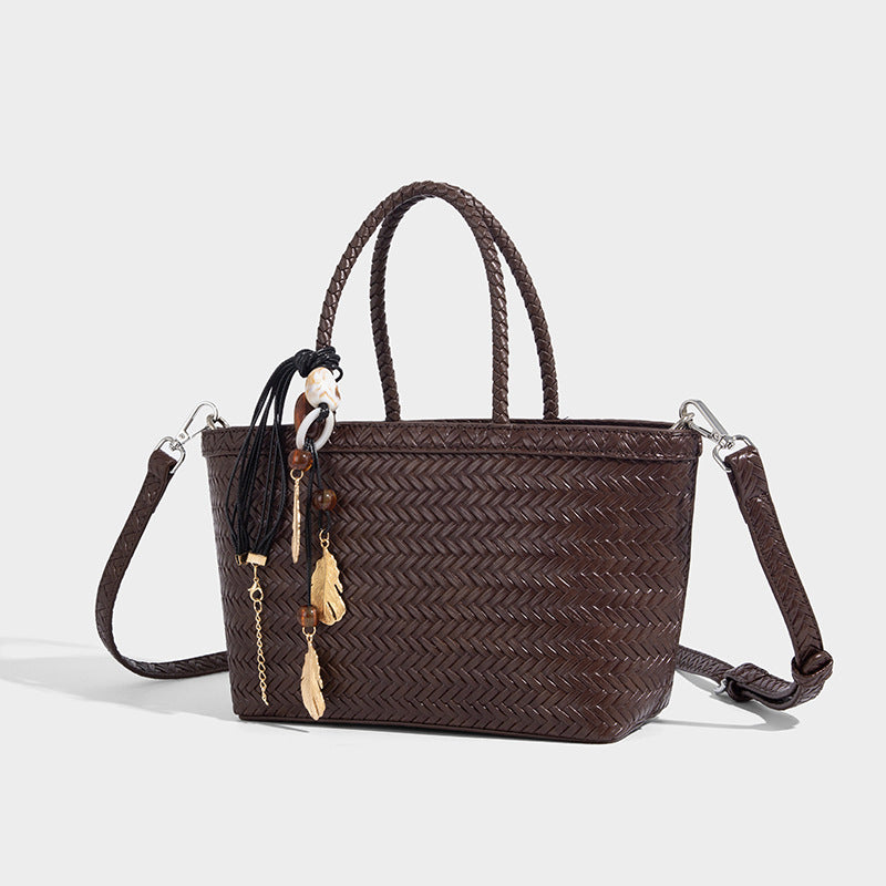 Structured chevron woven leather-look tote bag with braided top handles, gold feather charm, and adjustable shoulder strap