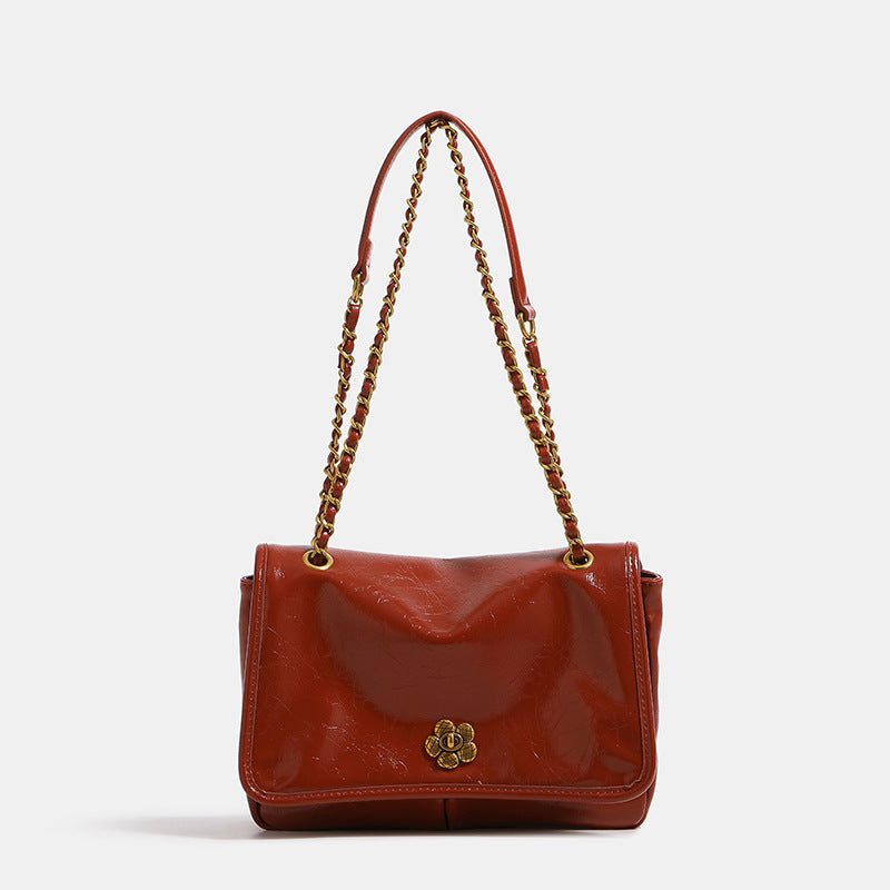 Structured flap shoulder bag with antique gold-tone chain strap and flower turn-lock clasp in crinkled leather-look finish