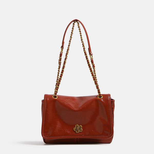 Structured flap shoulder bag with antique gold-tone chain strap and flower turn-lock clasp in crinkled leather-look finish