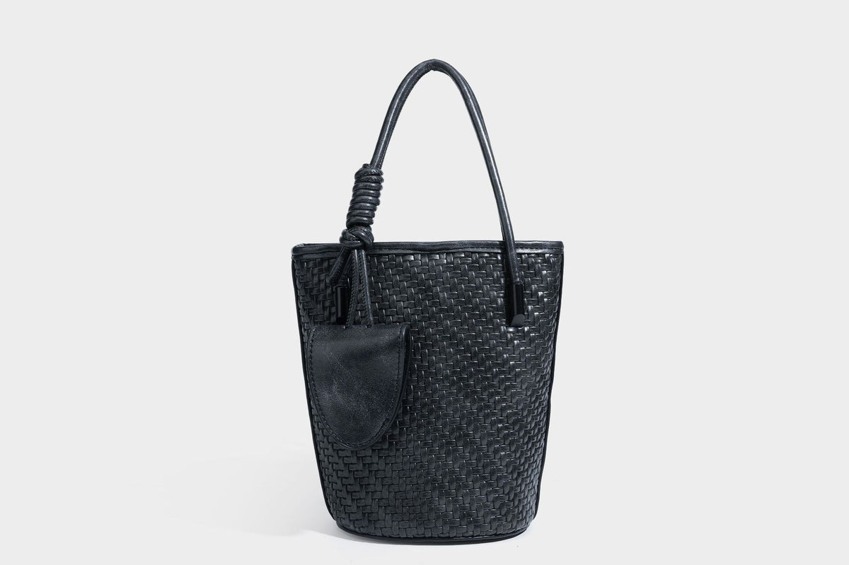 Structured woven-texture leather-look bucket bag in brown with knotted top handles, small front flap pouch, and adjustable