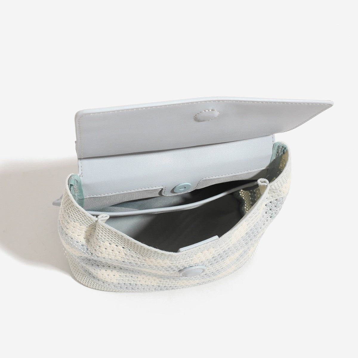 Small structured woven-body flap bag with smooth leather-look front panel, knotted top handle, and wide adjustable shoulder