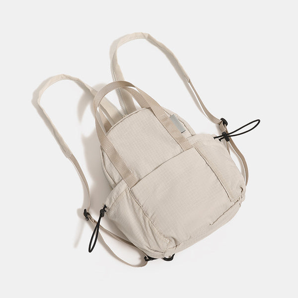 Small rounded mini backpack handbag in matte ripstop-texture fabric with top webbing handle, front pocket, side drawstring