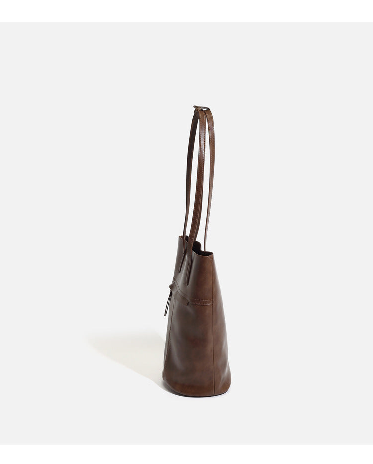 Large black smooth leather-look bucket tote bag with long shoulder straps and open top, detail view 9