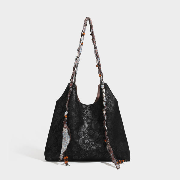 Slouchy paisley-embossed suede-look shoulder tote bag with braided patterned fabric straps and wood bead accents, detail view