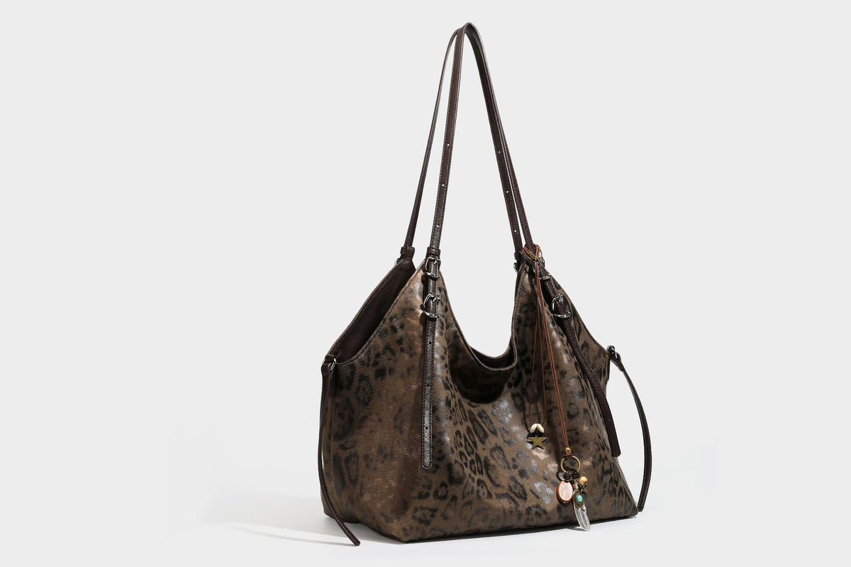 Slouchy leopard-print shoulder tote bag in tan and brown with long double straps, side tie straps, and dangling charm, detail