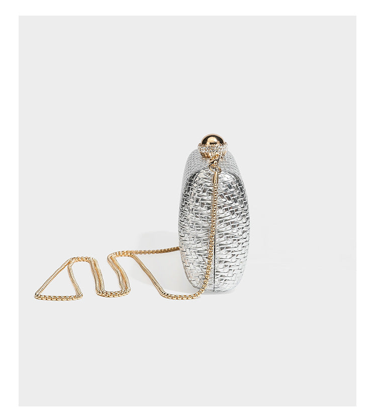 Small structured metallic woven-texture box clutch bag with jeweled kiss-lock dome clasp and slim gold chain strap, detail